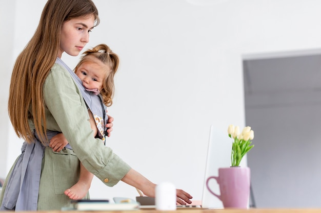 Free photo mother holding girl while working