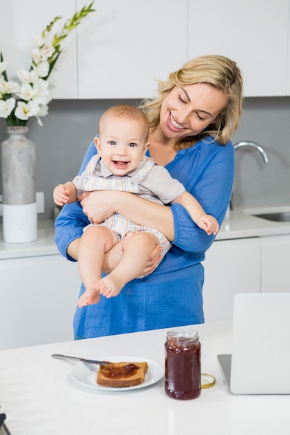 Mother holding her baby boy in kitchen