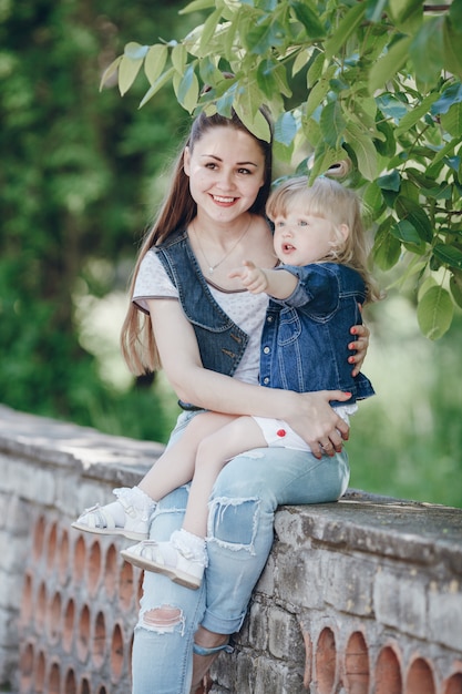 Mother holding her daughter in her arms sitting on a brick railing