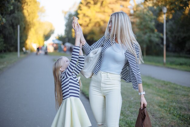 Mother holding an ice cream cone while her daughter tries to pick it up