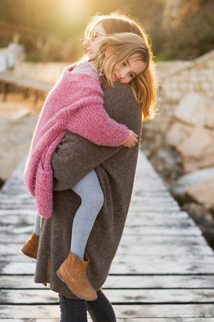 Free photo mother holding innocent daughter outdoors