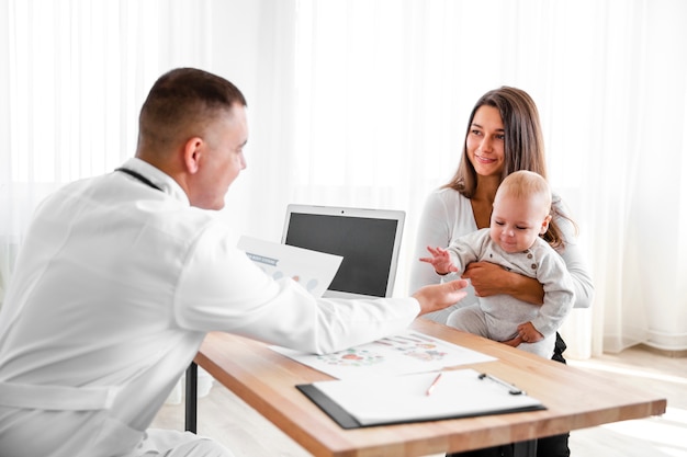 Mother holding little baby and looking at doctor