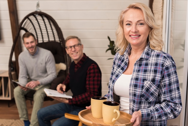 Mother holding tray of cups posing with family in the background