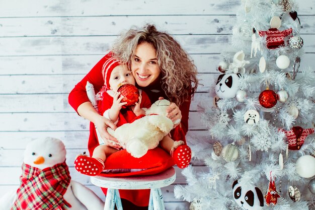 "Mother hugging baby daughter sitting on stool"