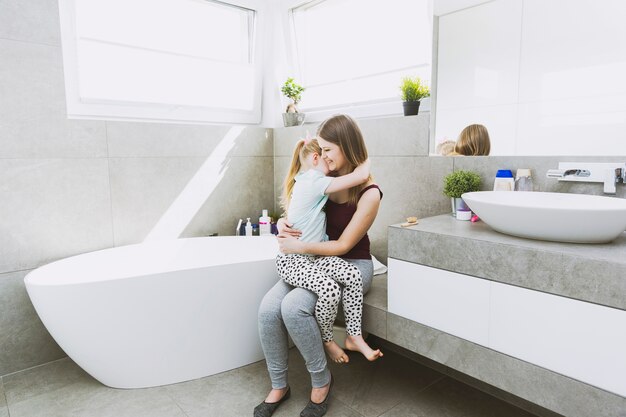 Mother hugging daughter in bathroom