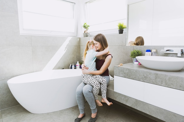 Mother hugging daughter in bathroom