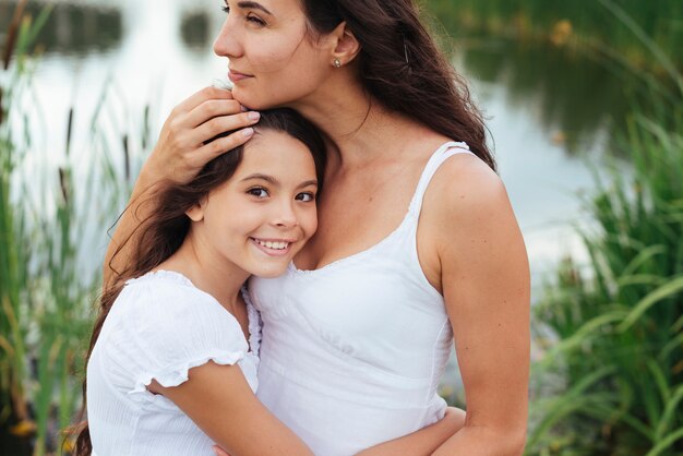 Мать обнимает дочь у озера