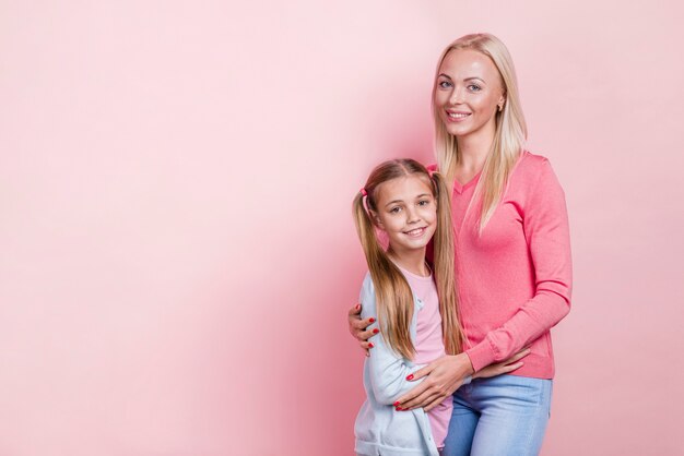 Mother hugging her daughter and copy space background