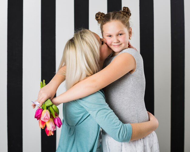 Mother hugging and kissing daughter