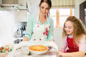 Free photo mother interacting with daughter while holding pancake in coolin