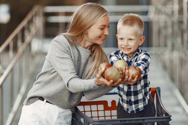 Mother is driving in a trolley. Family in a parking near a supermarket.