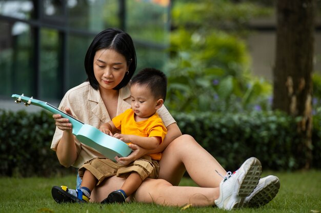 Mother and kid sitting on grass full shot