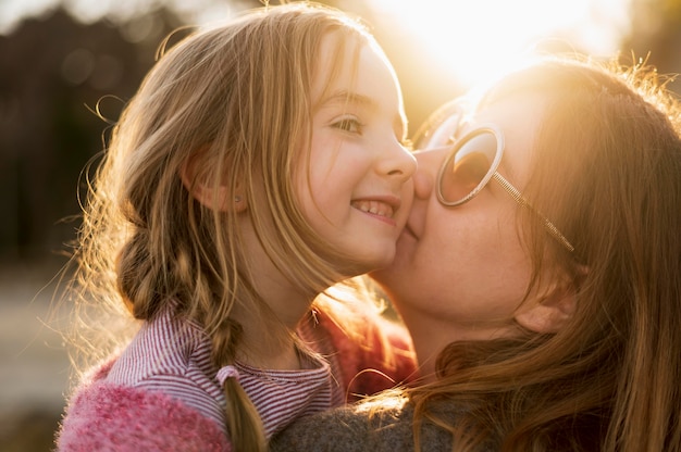 Free photo mother kissing adorable young girl