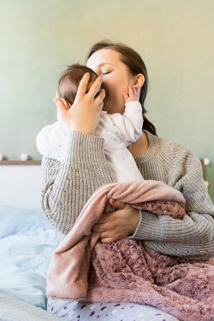 Mother kissing cute baby in arms