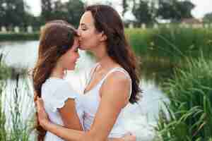 Free photo mother kissing daughter by the lake