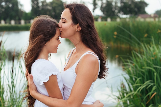 母は湖のそばで娘にキス