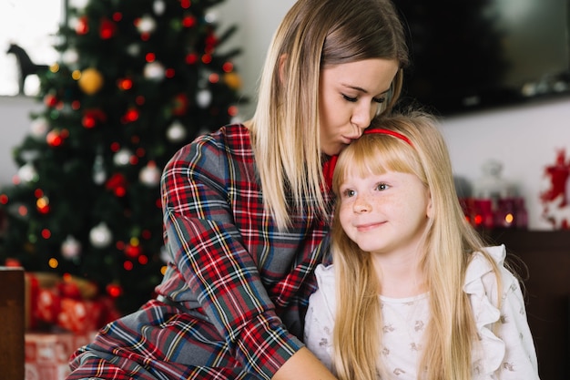 Free photo mother kissing daughter at christmas