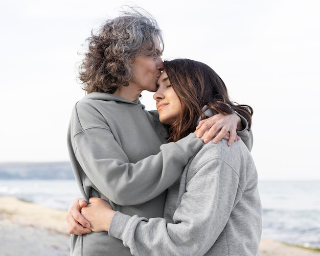 Free photo mother kissing daughter's forehead outdoors