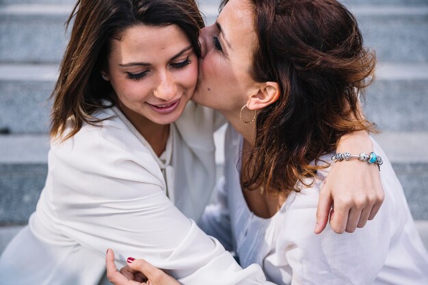 Mother kissing daughter on steps