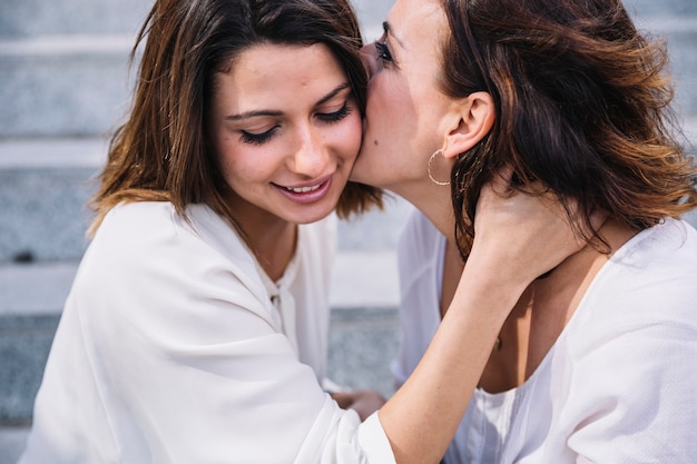 Free photo mother kissing daugther in cheek