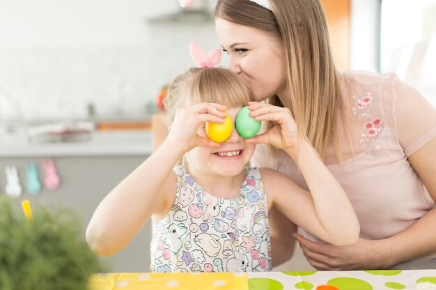 Mother kissing girl with aster eggs