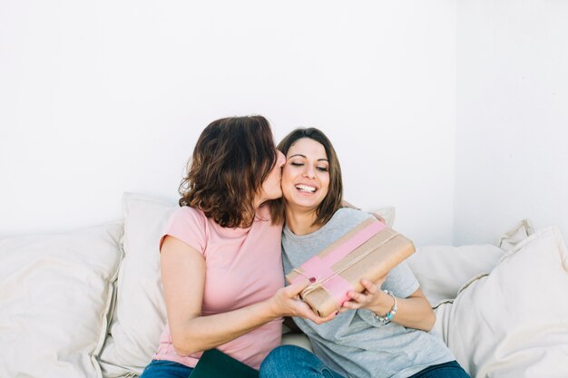 mother kissing woman for gift