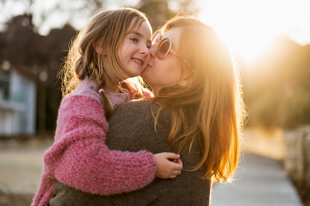 Free photo mother kissing young girl medium shot