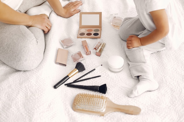 Mother and little daughter having fun at home with cosmetics