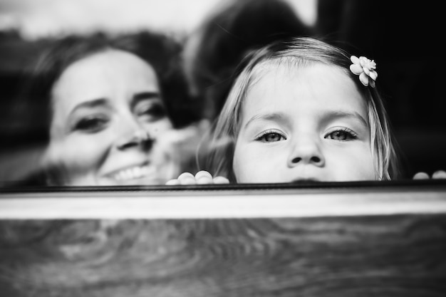 Mother and a little daughter look over the windowsill 