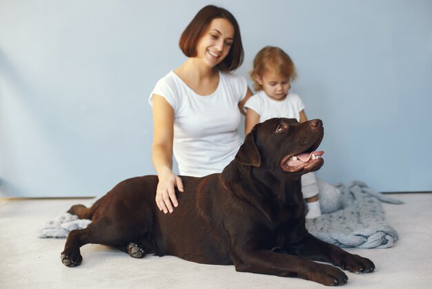 Mother and little daughter playing with dog at home