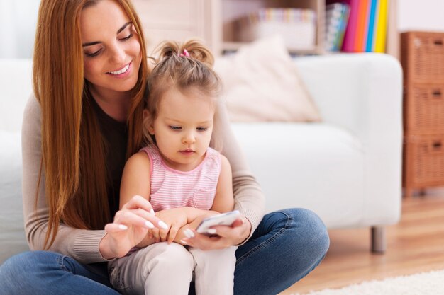 Mother and little girl using mobile phone at home