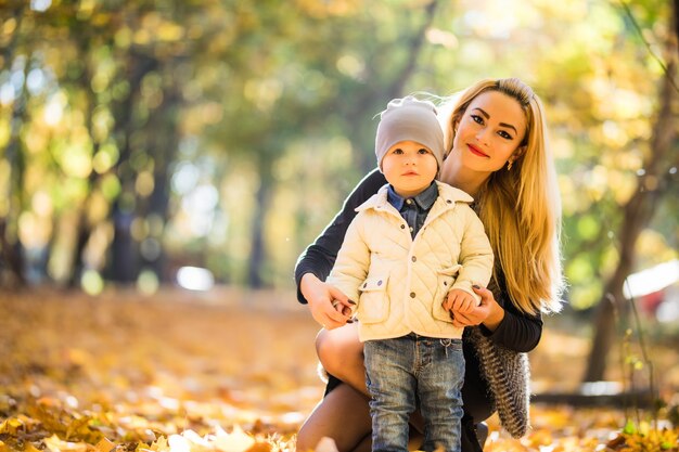 母と幼い息子の公園や森、屋外。秋の公園で抱き合って楽しんで