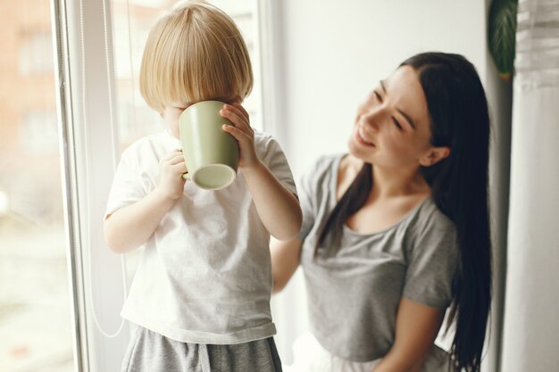 Mother and little son sitting on a windowsill with a tea