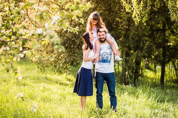 Free photo mother looking at daughter sitting on father's shoulder