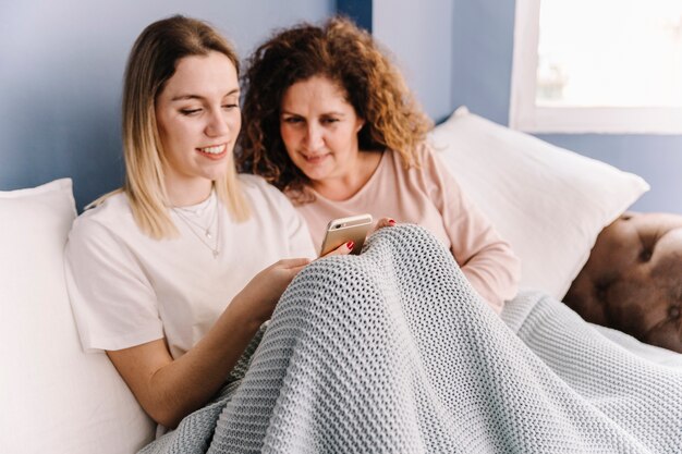 Mother looking at daughter using smartphone