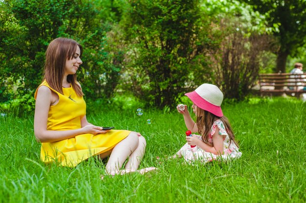 Mother looking at her little daughter making soap bubbles