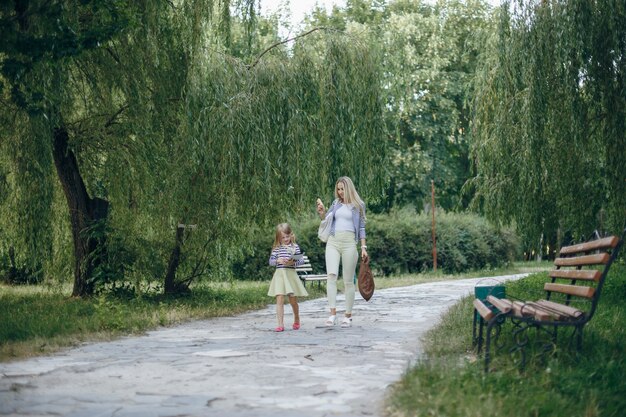 Mother looking at a smart phone while her daughter looks at a tablet in a park