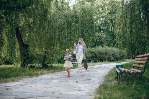 Mother looking at a smart phone while her daughter looks at a tablet in a park