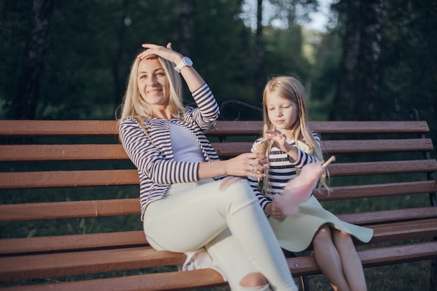 Mother looking at the sun while her daughter looks at the ice cream held by the mother