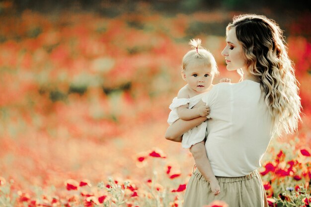 Mother looks at her baby on the poppy field
