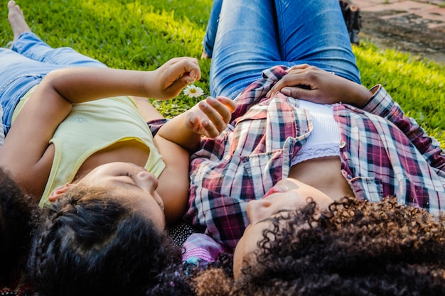 Free photo mother lying on the grass with daughter