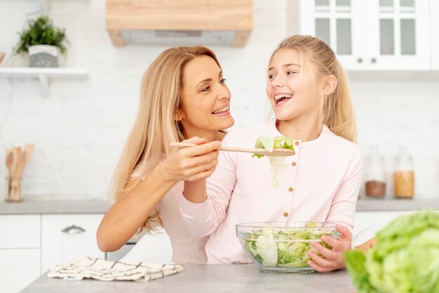 Mother offering salad to her daughter