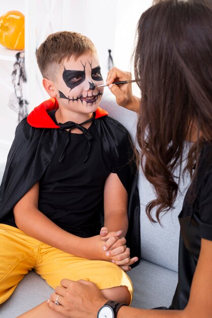 Mother painting her sons face for halloween