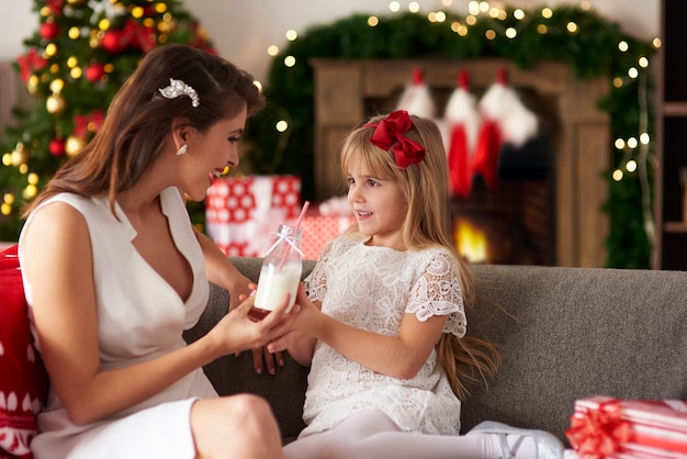 Mother passing bottle of milk to daughter