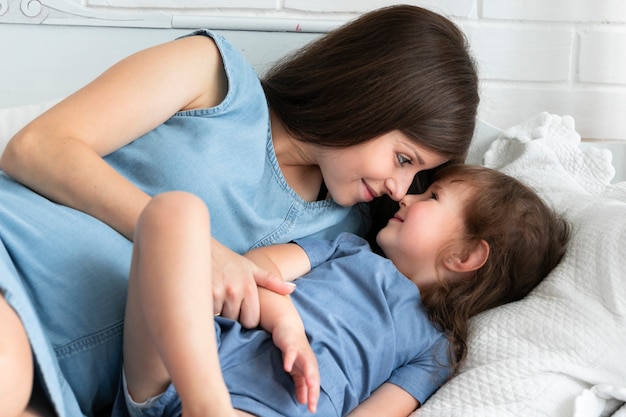 Mother playing in bed with her daughter