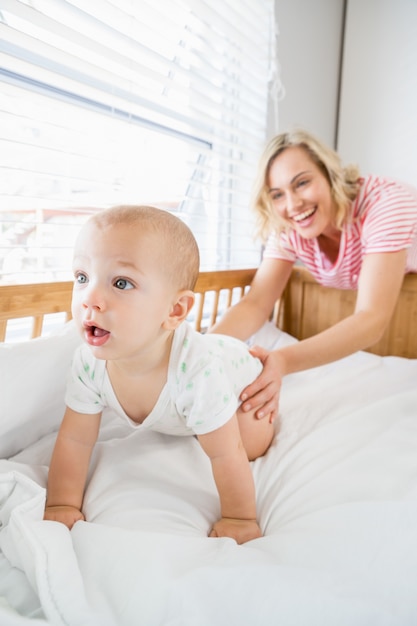 Free photo mother playing with her baby boy in cradle