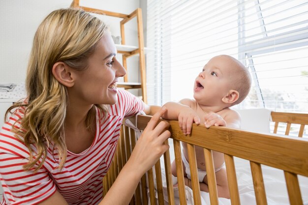 Mother playing with her baby boy in cradle