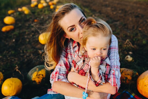 Mother playing with her daughter on a field with pumpkins