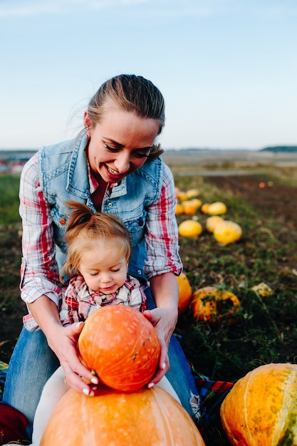 Free photo mother playing with her daughter with pumpkins