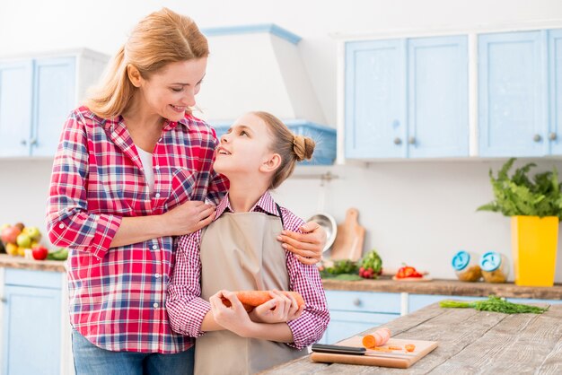 Mother pleasing her daughter holding carrot in hand